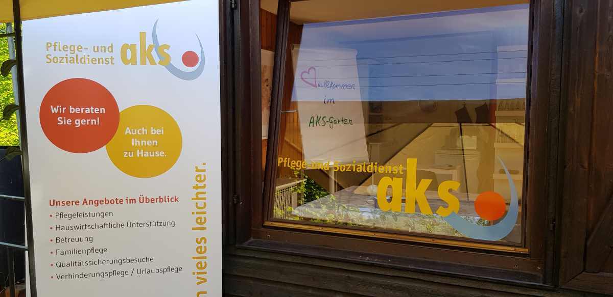 Window with stickers and poster from the care and social services agency aks with yellow and red lettering and dots